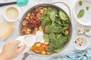 Spinach, sun-dried tomatoes and cream added to the skillet with chicken sausage and potato gnocchi.