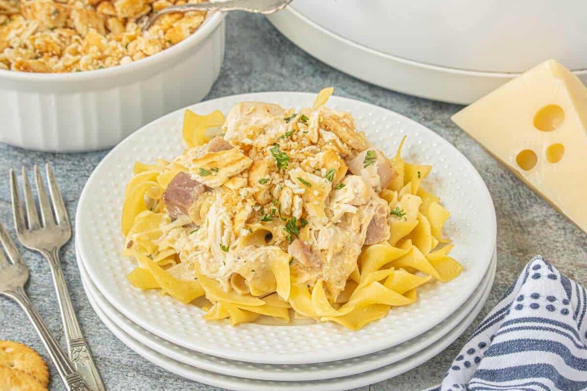 Crockpot chicken cordon blue served over egg noodles with ham, creamy sauce, Swiss cheese, and a buttery cracker topping.