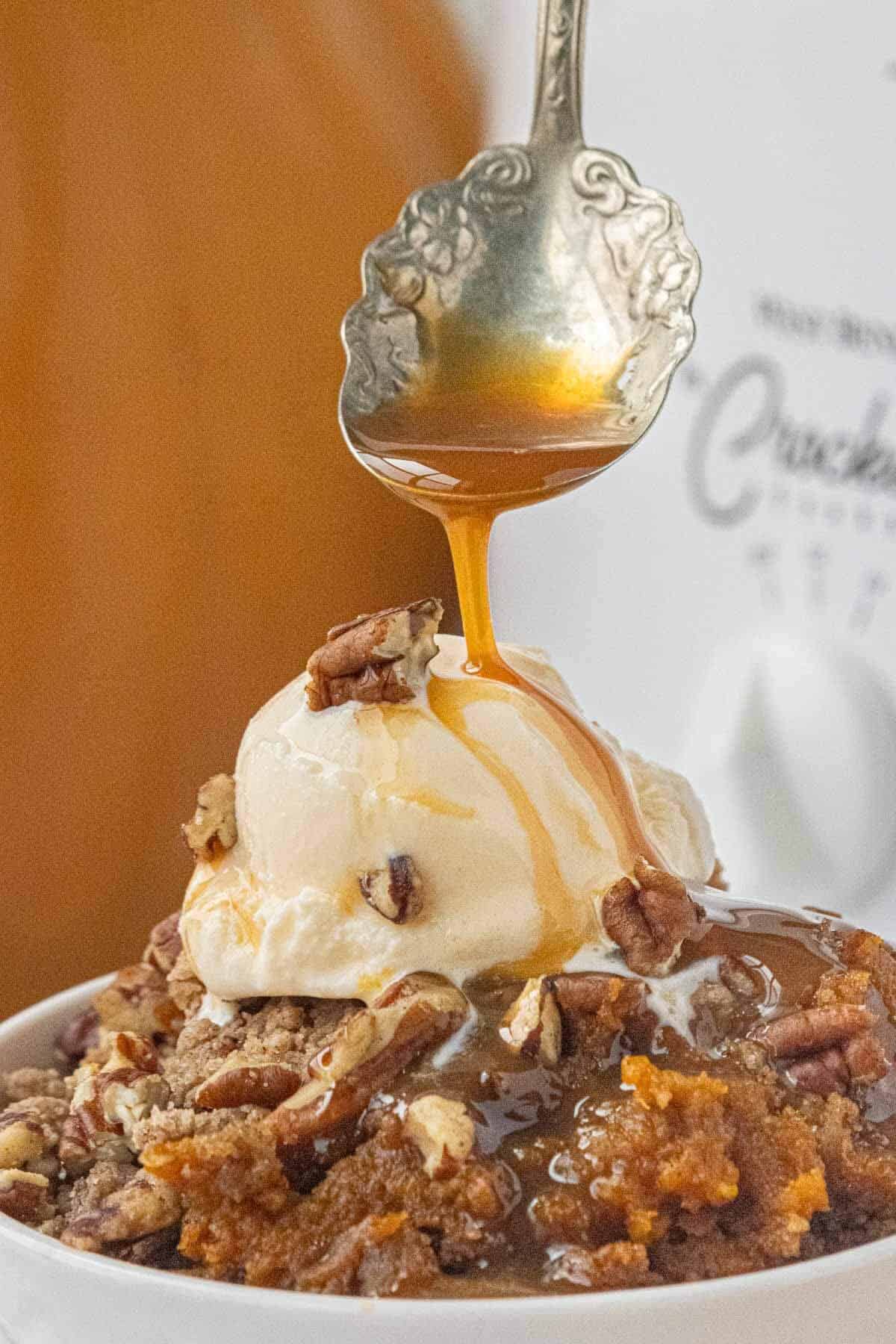 Bowl of Crockpot Pumpkin Dump Cake topped with buttery crumbles and chopped pecans.