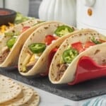Shredded beef tacos in soft flour tortillas topped with cheese, lettuce, tomatoes, jalapeños and sour cream.