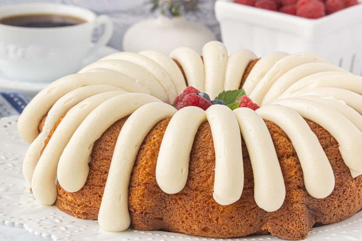 Copycat Nothing Bundt Vanilla Cake topped with thick cream cheese frosting and fresh berries.