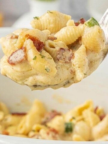Spoonful of creamy Bacon Jalapeño Mac and Cheese showing tender pasta shells coated in cheese sauce with pieces of smoky bacon and jalapeños.