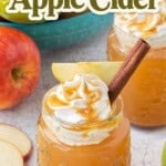 Pinterest pin featuring two mason jars of Crockpot Caramel Apple Cider topped with whipped cream, caramel drizzle, apple slices, and cinnamon sticks, with fresh apples and bold recipe title overlay.