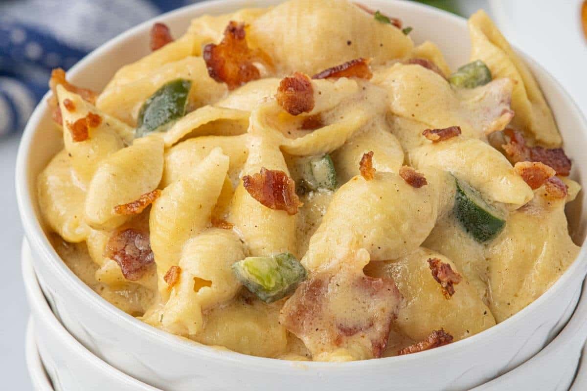 White bowl filled with creamy Crockpot Bacon Jalapeño Mac and Cheese, featuring tender pasta shells, diced jalapeños, and crispy bacon pieces.