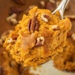 Close-up of a spoonful of spiced pumpkin dessert with golden brown edges and pecan pieces.