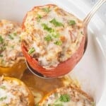 Close-up of a Stuffed Bell Pepper being lifted from the crockpot with a serving spoon. The peppers are filled with seasoned ground beef, rice, and sauce.